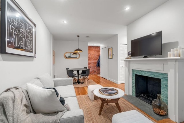 living area featuring recessed lighting, visible vents, wood finished floors, a tile fireplace, and baseboards