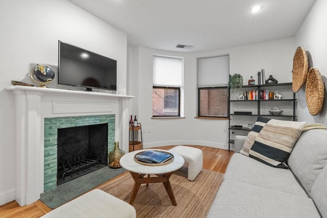 living area featuring a fireplace, wood finished floors, visible vents, and baseboards