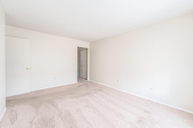 spare room with light colored carpet and baseboards