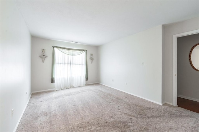 carpeted spare room with visible vents and baseboards