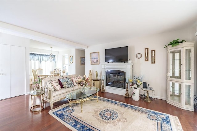 living area featuring a glass covered fireplace, wood finished floors, and a chandelier