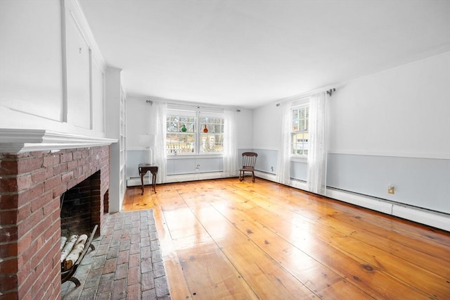 unfurnished living room featuring a healthy amount of sunlight, a brick fireplace, and hardwood / wood-style flooring