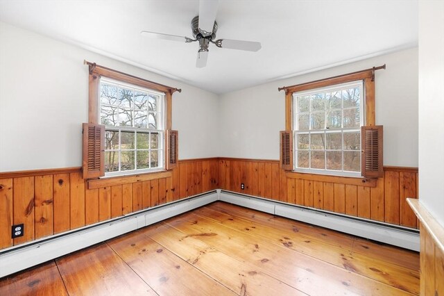 spare room featuring a wainscoted wall, ceiling fan, and wooden walls