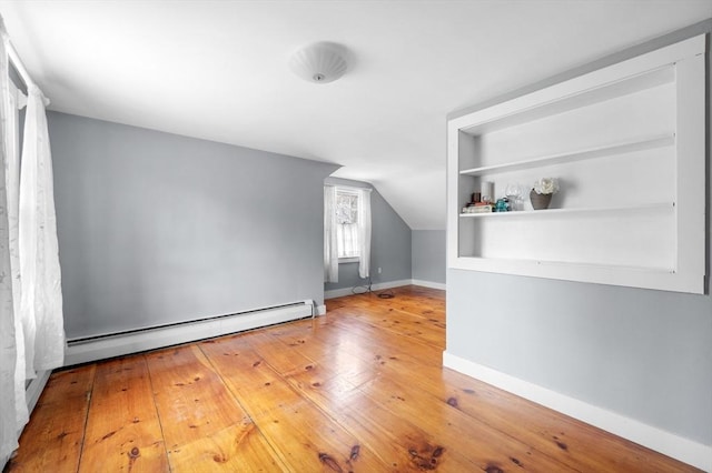 bonus room with built in shelves, a baseboard radiator, hardwood / wood-style flooring, baseboards, and vaulted ceiling