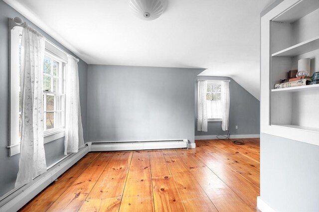 bonus room with a healthy amount of sunlight, baseboard heating, and hardwood / wood-style flooring