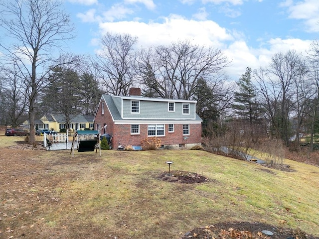 back of house with a chimney, a lawn, and brick siding