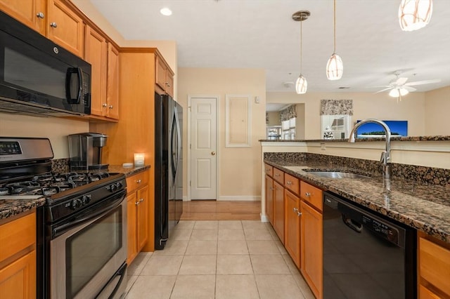 kitchen featuring decorative light fixtures, sink, black appliances, and dark stone counters