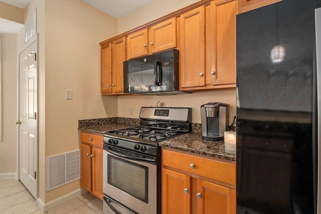 kitchen featuring light tile patterned floors, black appliances, and dark stone counters