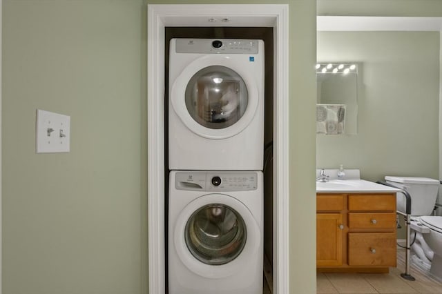 clothes washing area featuring sink, stacked washing maching and dryer, and light tile patterned flooring