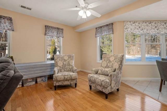 living area with ceiling fan, light hardwood / wood-style floors, and a wealth of natural light