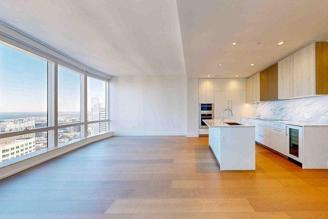 kitchen featuring light countertops, an island with sink, and modern cabinets