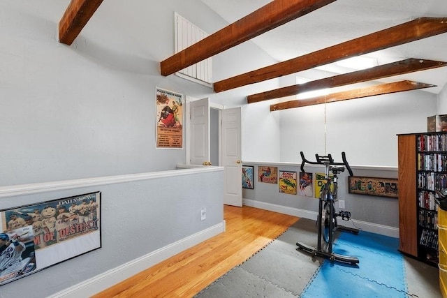 exercise area featuring a notable chandelier, baseboards, lofted ceiling, and wood finished floors