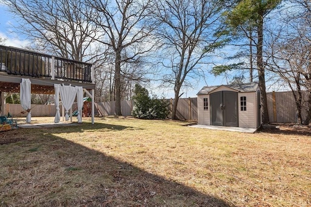 view of yard featuring an outbuilding, a fenced backyard, a shed, and a patio