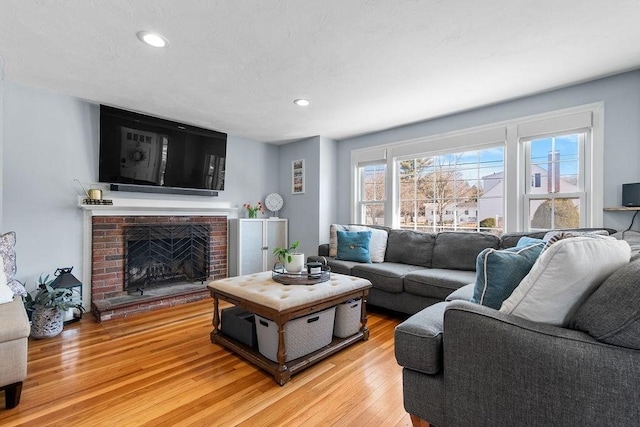 living room featuring recessed lighting, a fireplace, and light wood-style floors