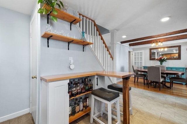 bar featuring baseboards, stairs, recessed lighting, an inviting chandelier, and light wood-style floors