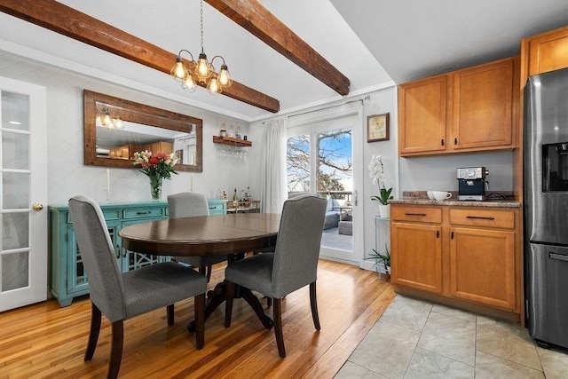 dining area with light wood finished floors, beamed ceiling, and an inviting chandelier