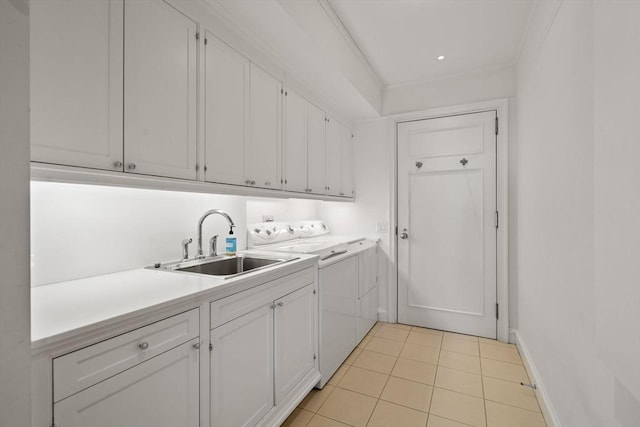 clothes washing area featuring light tile patterned flooring, baseboards, separate washer and dryer, a sink, and cabinet space
