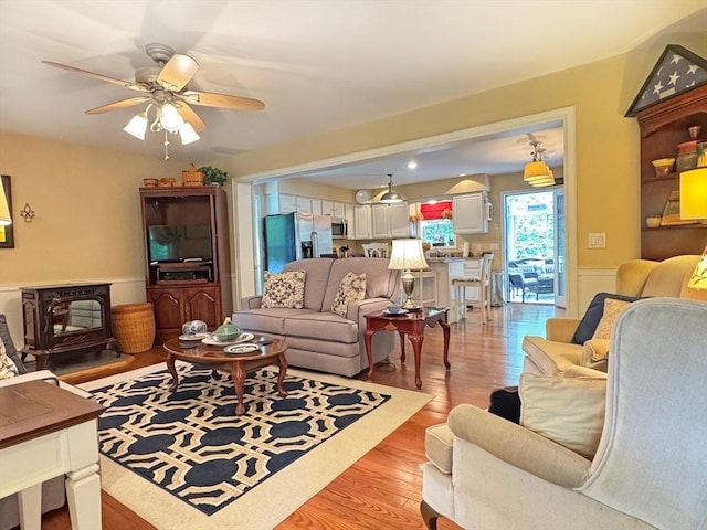 19 Orange Rd, Northfield, MA 01360 - living room with a wood stove, light wood-style floors, a ceiling fan, and wainscoting