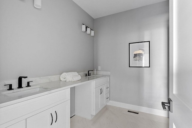 bathroom with marble finish floor, double vanity, a sink, and visible vents