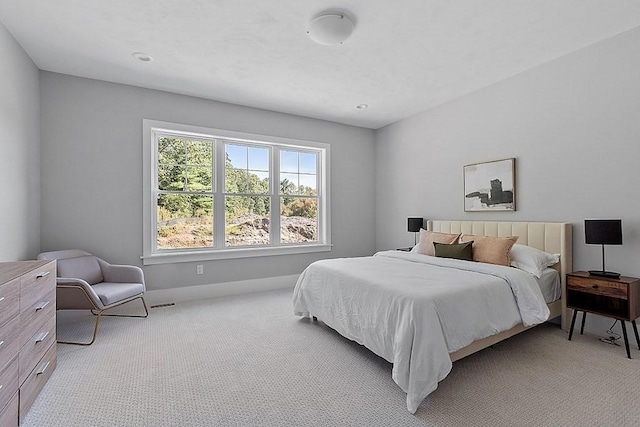 bedroom with baseboards, visible vents, and light colored carpet