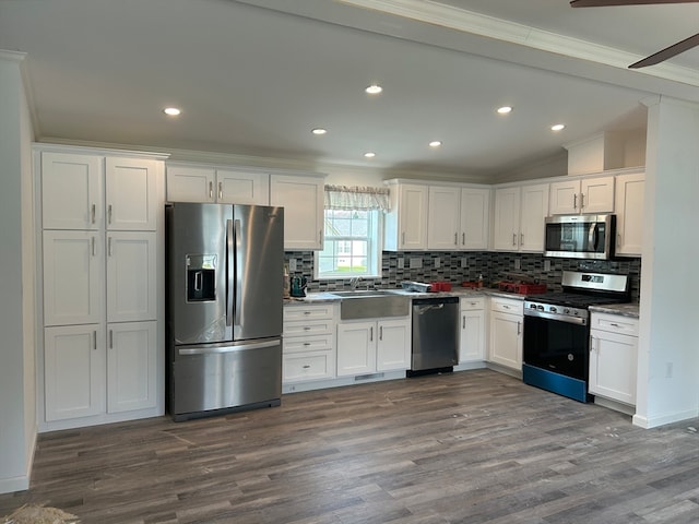 kitchen featuring crown molding, backsplash, appliances with stainless steel finishes, dark hardwood / wood-style floors, and white cabinets