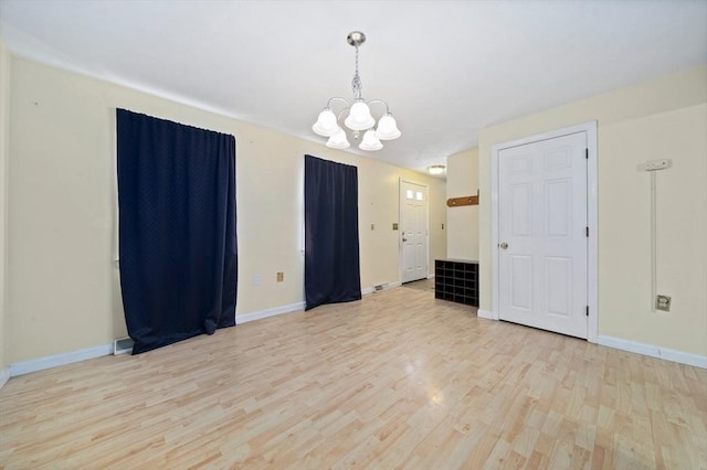 spare room featuring light hardwood / wood-style floors and a notable chandelier