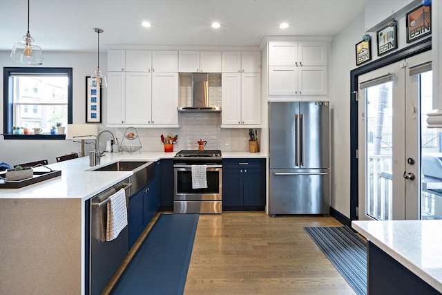 kitchen with appliances with stainless steel finishes, wall chimney range hood, plenty of natural light, a sink, and recessed lighting