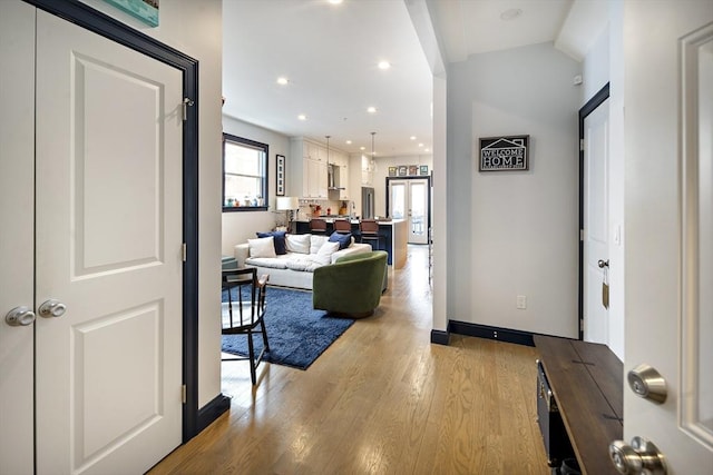 hallway with light wood finished floors, recessed lighting, and baseboards