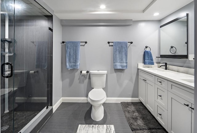 bathroom with a stall shower, double vanity, toilet, baseboards, and recessed lighting