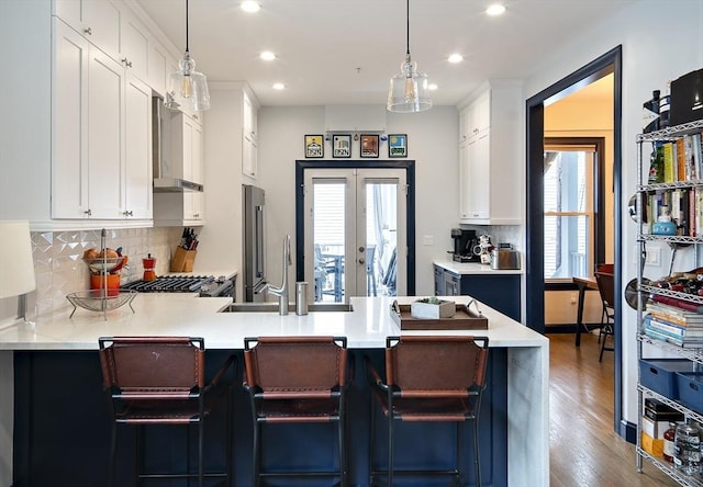 kitchen with recessed lighting, light countertops, a peninsula, white cabinetry, and wood finished floors