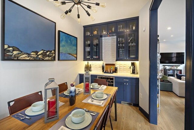 dining space with bar with sink, light wood-style flooring, and recessed lighting