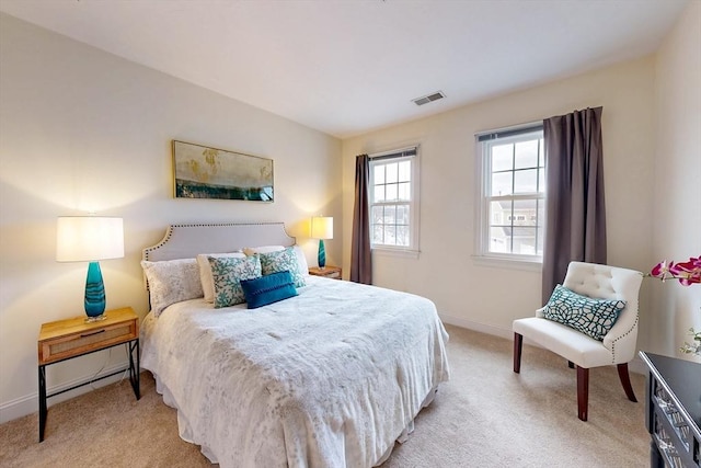 bedroom with baseboards, visible vents, and light colored carpet