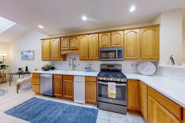 kitchen with light tile patterned floors, light countertops, appliances with stainless steel finishes, and decorative backsplash