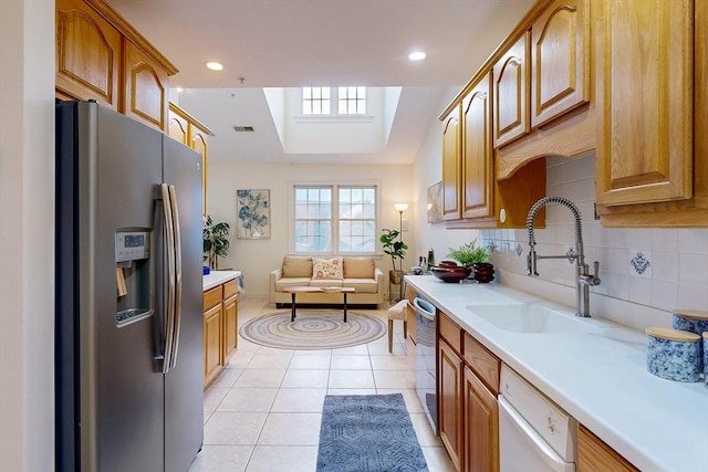 kitchen with light tile patterned floors, a sink, light countertops, appliances with stainless steel finishes, and tasteful backsplash