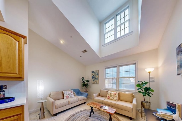 living room featuring high vaulted ceiling, a healthy amount of sunlight, and light tile patterned floors