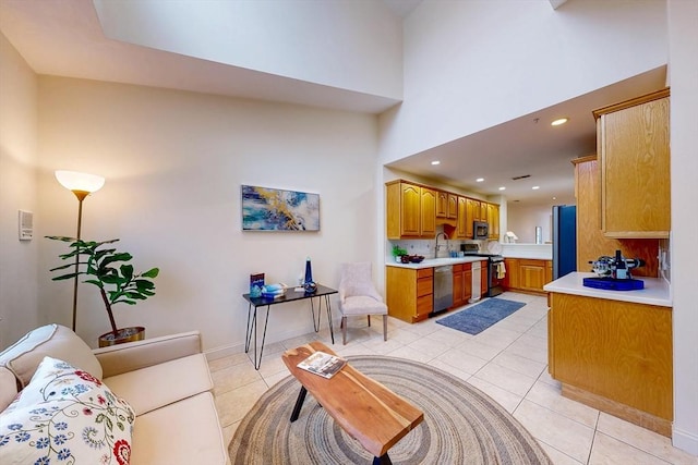 living area with a towering ceiling, recessed lighting, baseboards, and light tile patterned flooring