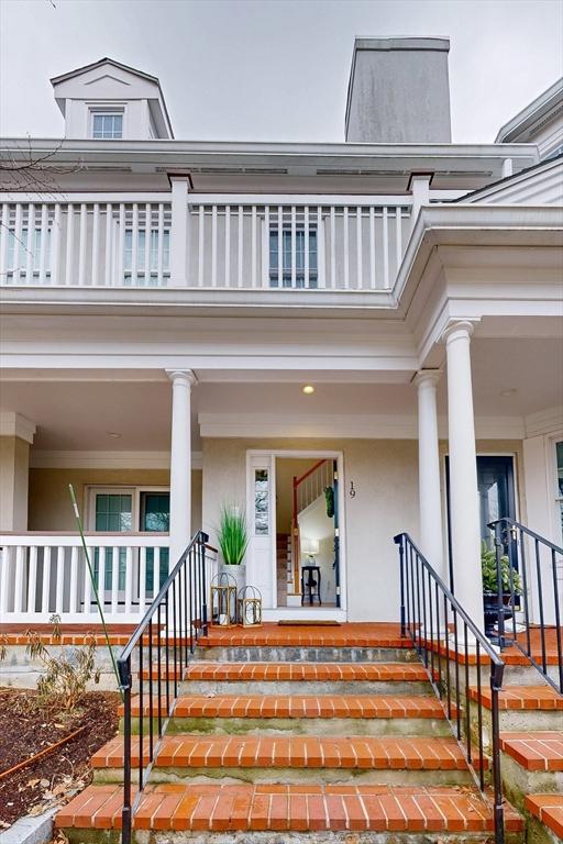 entrance to property featuring a balcony, a porch, and stucco siding