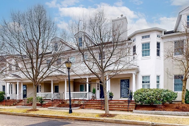 multi unit property featuring a chimney, a porch, and stucco siding