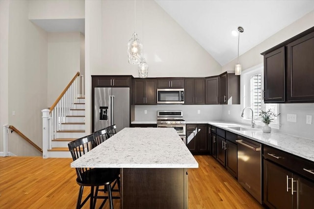 kitchen with light wood-type flooring, a sink, a kitchen breakfast bar, a center island, and appliances with stainless steel finishes