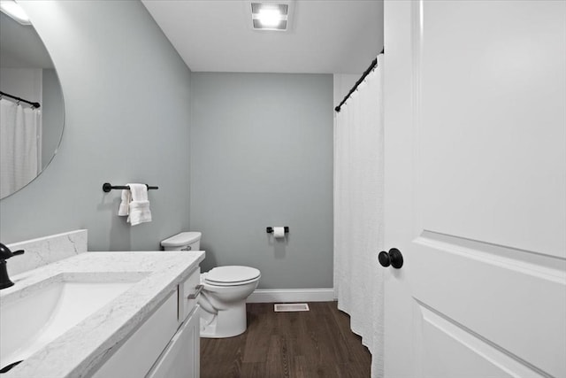 bathroom featuring visible vents, toilet, wood finished floors, baseboards, and vanity