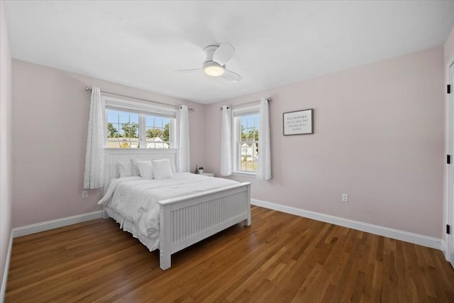 bedroom featuring baseboards, multiple windows, wood finished floors, and a ceiling fan