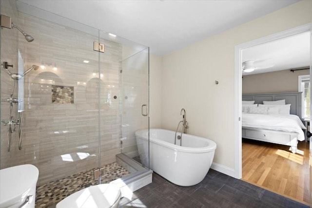 ensuite bathroom featuring wood finished floors, a stall shower, a freestanding bath, ensuite bathroom, and toilet