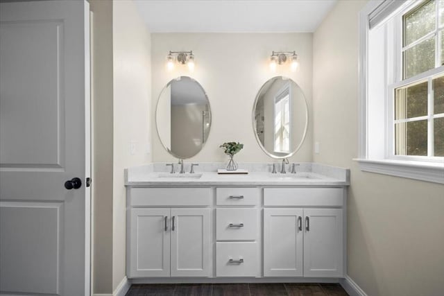 bathroom featuring a sink, baseboards, and double vanity