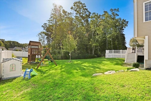 view of yard featuring a playground, a deck, and fence