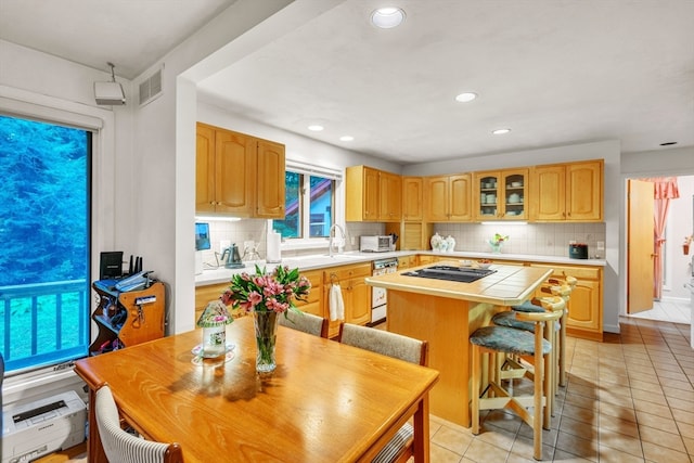 kitchen with tasteful backsplash, a kitchen breakfast bar, dishwasher, a kitchen island, and light tile patterned flooring