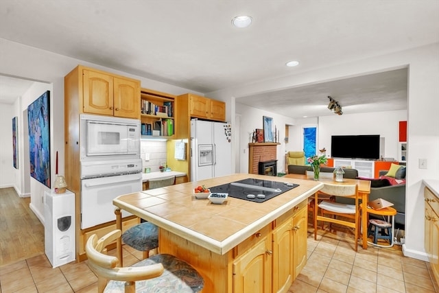 kitchen with tile countertops, white appliances, light tile patterned floors, and a brick fireplace