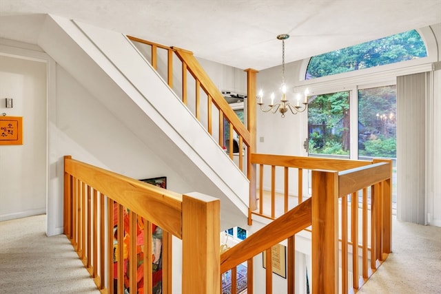 staircase with an inviting chandelier and carpet floors