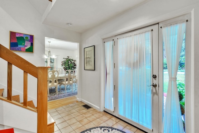 tiled entryway featuring a notable chandelier