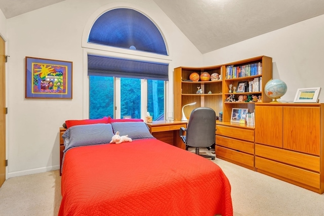 carpeted bedroom featuring built in desk and vaulted ceiling