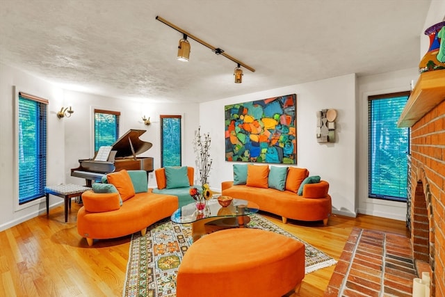 living room featuring a fireplace, a textured ceiling, rail lighting, and hardwood / wood-style floors